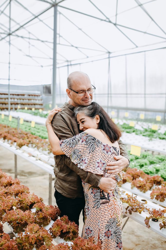 Couple embracing in a greenhouse, after discussing their finances.